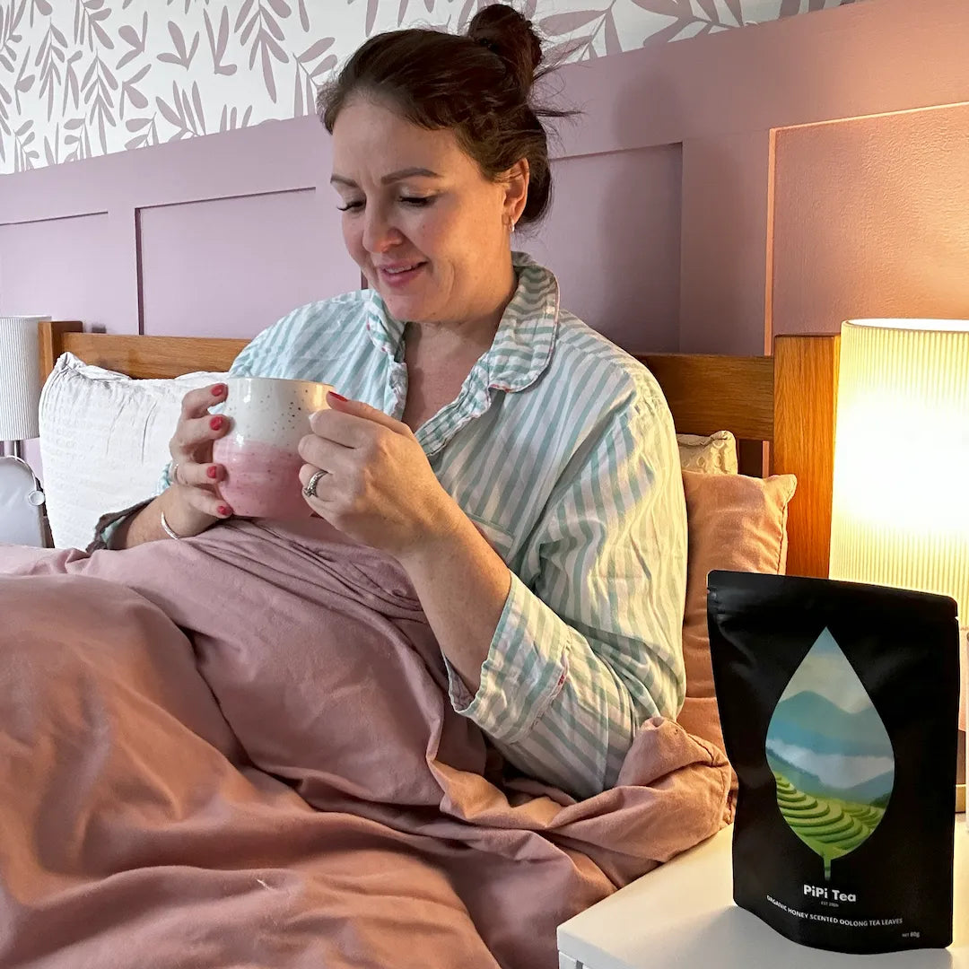 A person stirs a glass of iced hibiscus tea next to a pouch of Pipi Tea tea bags.